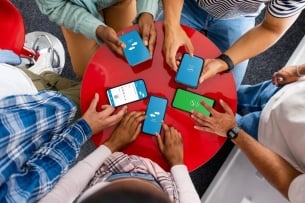 Overhead shot of students sitting around a round table with their smartphones out.